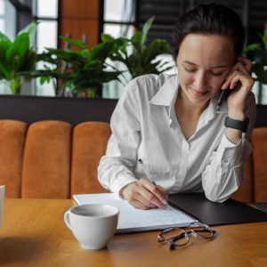 Female small business owner working on a laptop in a cozy home office with coffee, representing real-life entrepreneurship, sales, and marketing for small businesses.